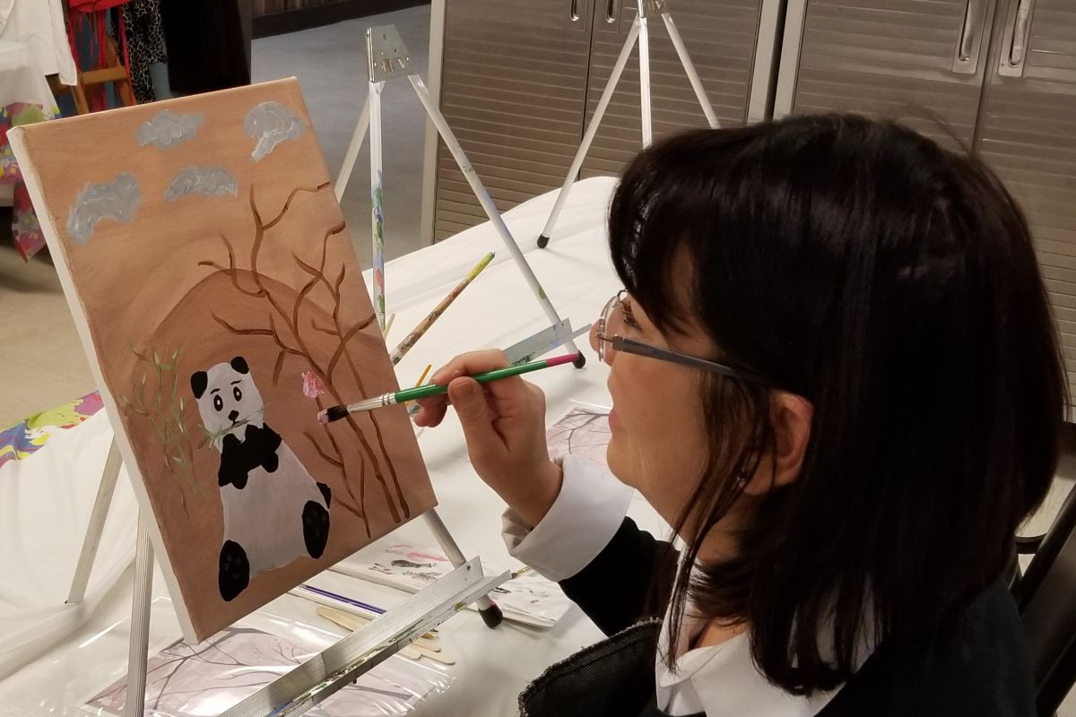 woman painting panda on canvas