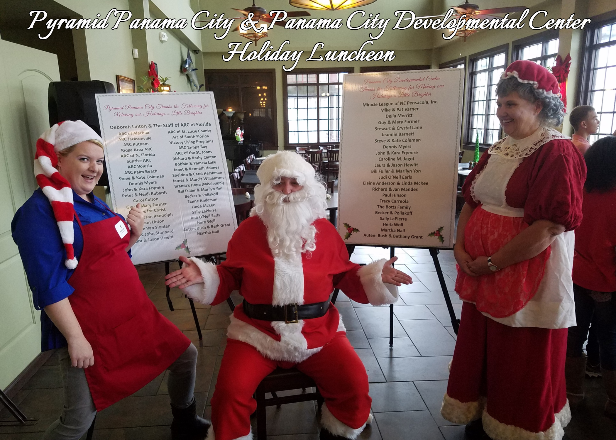 Santa, Mrs. Claus and Elf in front of thank you signs
